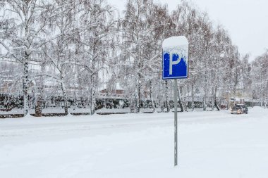 Bir kış günü kar yağışı sırasında karlı bir caddede yol tabelası. Yol işareti park ettiğini gösteriyor. Karla kaplı caddeye park etmek. Kışın anormal miktardaki kar yağışı.