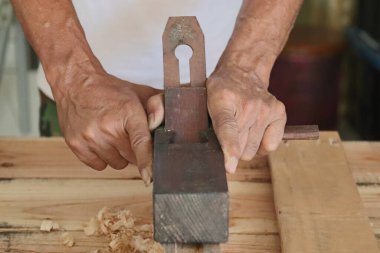 A carpenter adjusts the crossbow by hand with a hand planer.