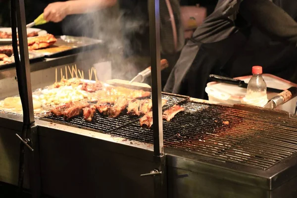 Barbecue grilling meat to sell to customers at a street food market. Well-known street food for both Thais and foreigners in Bangkok, Thailand.