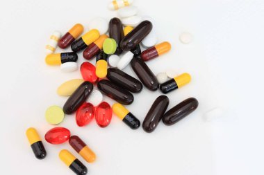 Masanın üzerinde çeşitli ilaç hapları, haplar ve kapsüller var. Ortasında seçici bir odak noktası var.