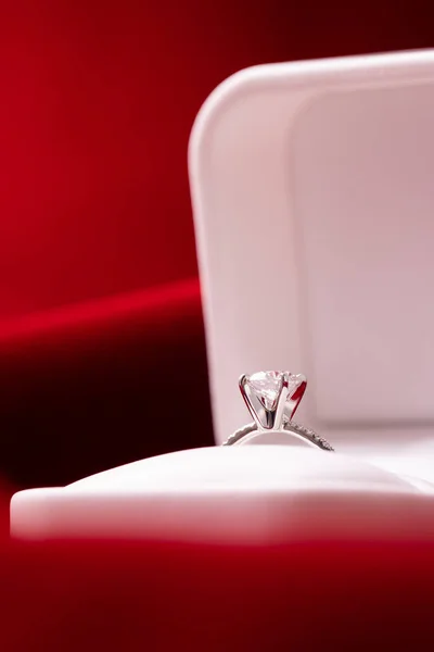 Diamond engagement or wedding ring in a box on red fabric