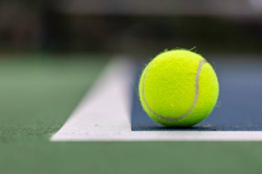 Tennis ball on the ground just inside the court lines