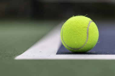 Tennis ball on the ground just inside the court lines