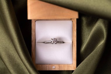 Diamond wedding or engagement ring in a box on green fabric