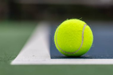 Tennis ball on the ground just inside the court lines