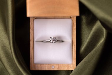 Diamond wedding or engagement ring in a box on green fabric