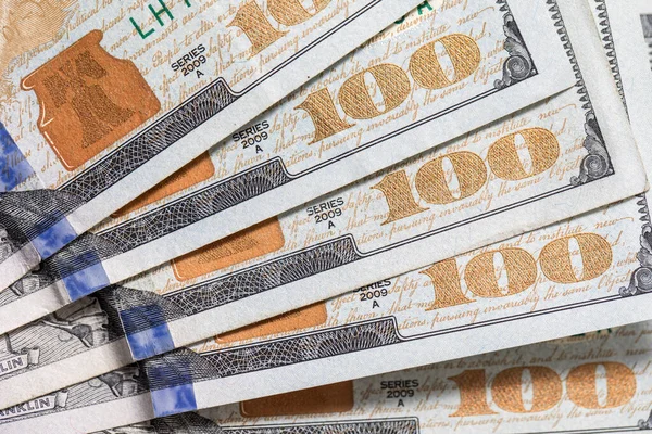 One hundred 100 dollar bills shot against a white background