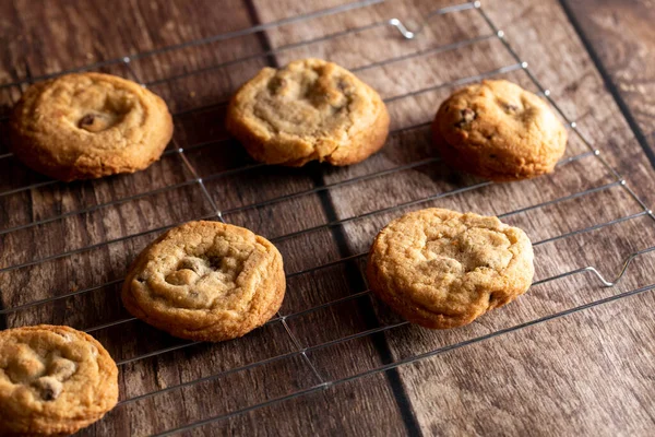 Chocolate chip cookies on a cooling rack on top of a dark wood background