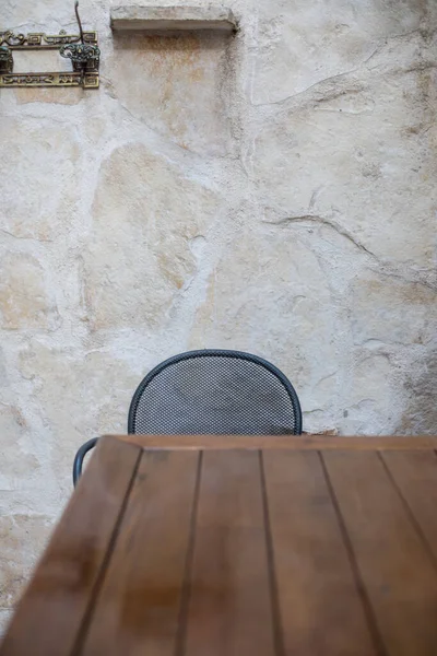 A chair at a table on the outdoor patio with a stone background