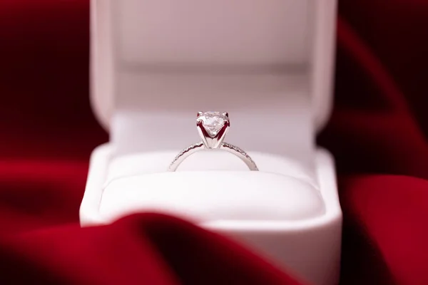 Diamond engagement or wedding ring in a box on red fabric