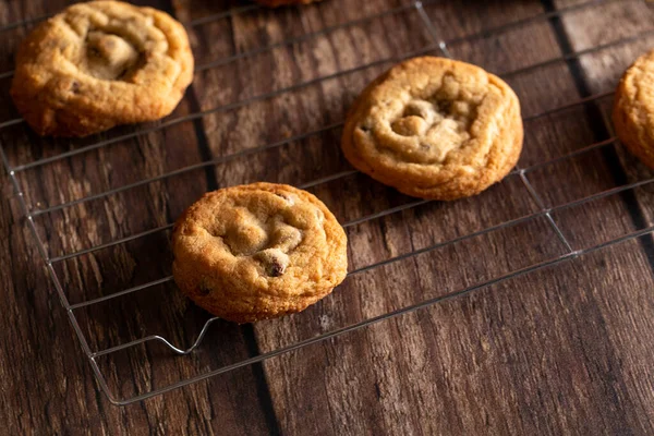 Chocolate chip cookies on a cooling rack on top of a dark wood background