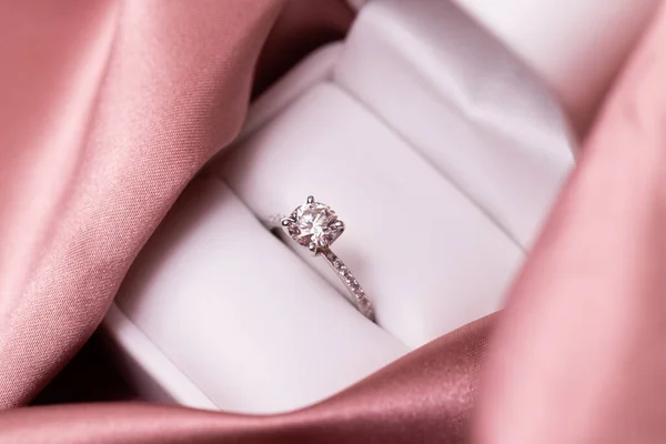 Diamond wedding or engagement ring in a box on pink fabric