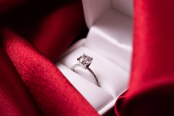 Diamond engagement or wedding ring in a box on red fabric