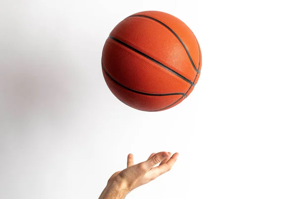 Male tossing a basketball in his hand on a white background
