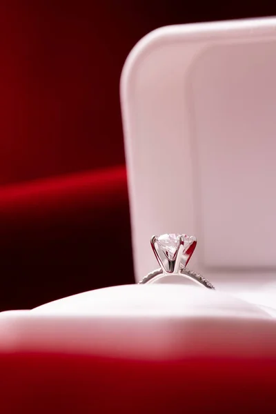 Diamond engagement or wedding ring in a box on red fabric