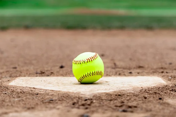 Softball laying on a worn home plate or base