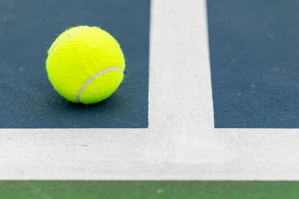 Tennis ball on the ground just inside the court lines