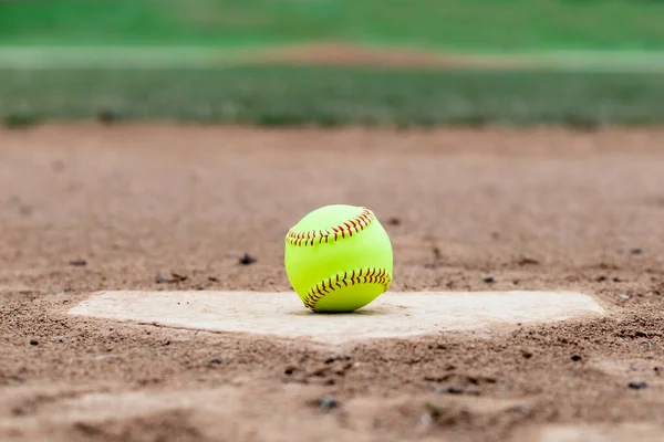 Softball laying on a worn home plate or base