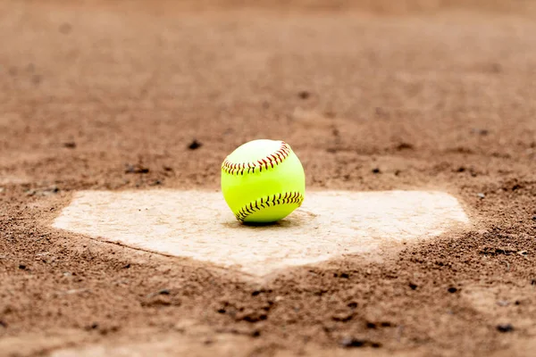 Softball laying on a worn home plate or base