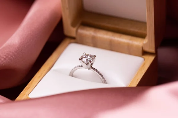 Diamond wedding or engagement ring in a box on pink fabric