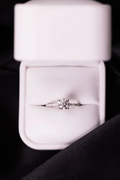 Diamond wedding or engagement ring in a box on black fabric