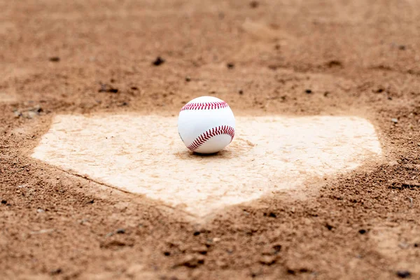 Baseball laying on a worn home plate or base