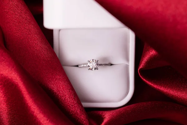 Diamond engagement or wedding ring in a box on red fabric
