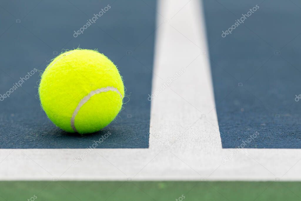 Tennis ball on the ground just inside the court lines