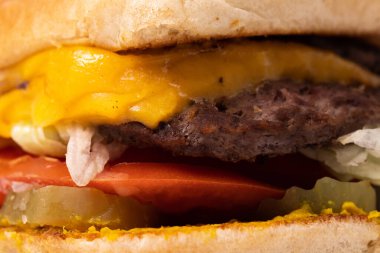 Fast food version of a cheeseburger with lettuce, pickle, and tomato
