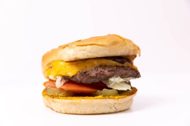 Fast food version of a cheeseburger with lettuce, pickle, and tomato