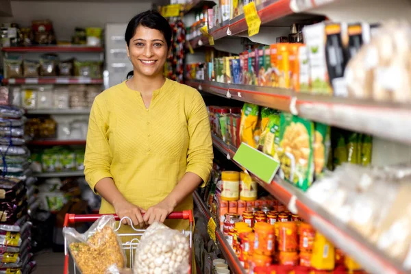 Woman with shopping trolley in supermarket.