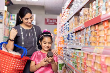 Happy mother and daughter reading product information while shopping at supermarket
