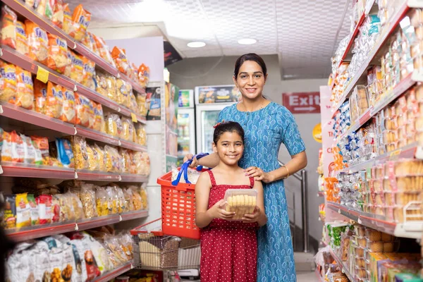 Mutlu anne ve kız süpermarkette alışveriş yaparken ürün bilgileri okuyor.