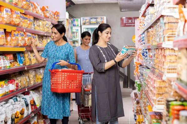 Kadınlar süpermarkette birlikte alışveriş yapıyor.
