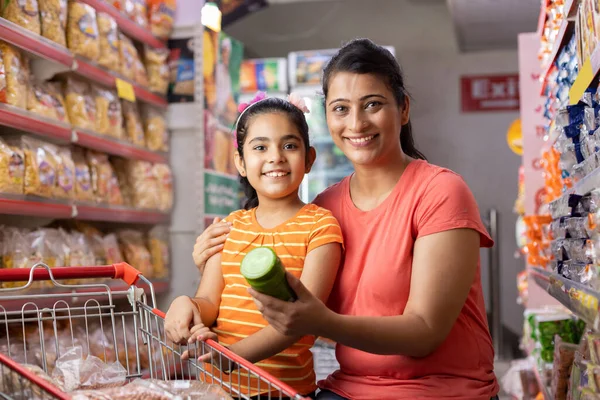 Mutlu anne ve kız süpermarkette alışveriş yaparken ürün bilgileri okuyor.
