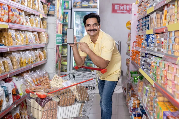 Markette boş bir cep telefonu ekranı gösteren mutlu adam.