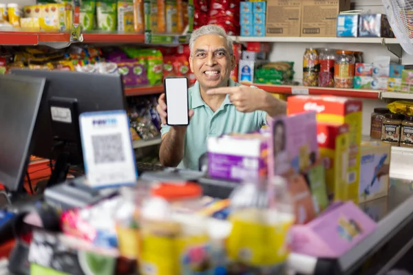 Portrait of happy man showing mobile phone screen at supermarket