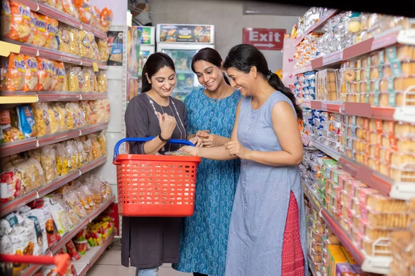 Kadınlar süpermarkette birlikte alışveriş yapıyor.