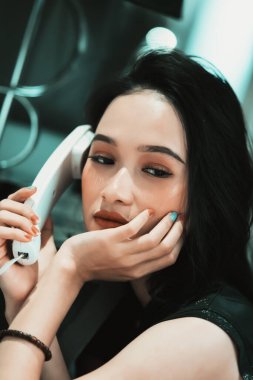 Asyalı kadınlar ellerinde siyah bir elbise ve bilezik ile bir telefon görüşmesi yaparlar. Telefonu tutar ve kulaklarına takar.