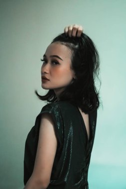 Siyah saçlarına dokunarak poz veren Asyalı manken siyah bir elbise giyerken seksi ve seksi hissediyordu.