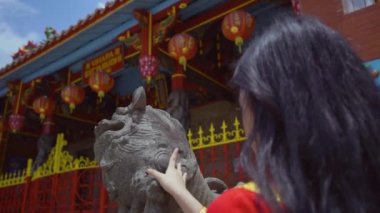 A Beautiful Chinese woman touching the Chinese statue while visiting the Buddhist temple in china town