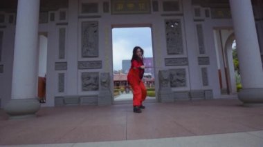 A Chinese Warrior with a red dress practicing the sword for the next battle inside the Chinese temple