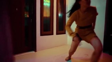 Asian Woman Climbing the wall fence while dancing using orange clothes in dark night