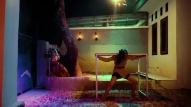 Beautiful Asian women dancing near the table with anger while wearing orange clothes in the dark night