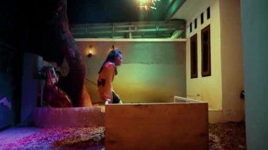 Asian Women use the broken table as their property to dance with it in the dark night
