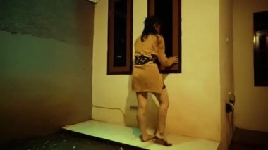 Desperate Asian Woman dancing with anger while wearing orange clothes in the dark night