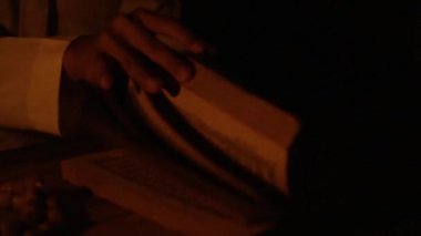 A Muslim man hands opening the book of Holly Qur'an near the fire torchlight at the night