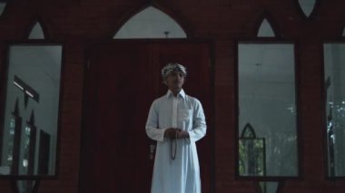 Muslim men standing and praying in front of the brown mosque during the morning in the village