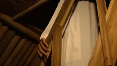 Muslim men down the stairs in his bamboo house while wearing white clothes in the village
