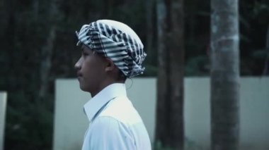 A Muslim man with white clothes walking lonely in the forest while visiting the village